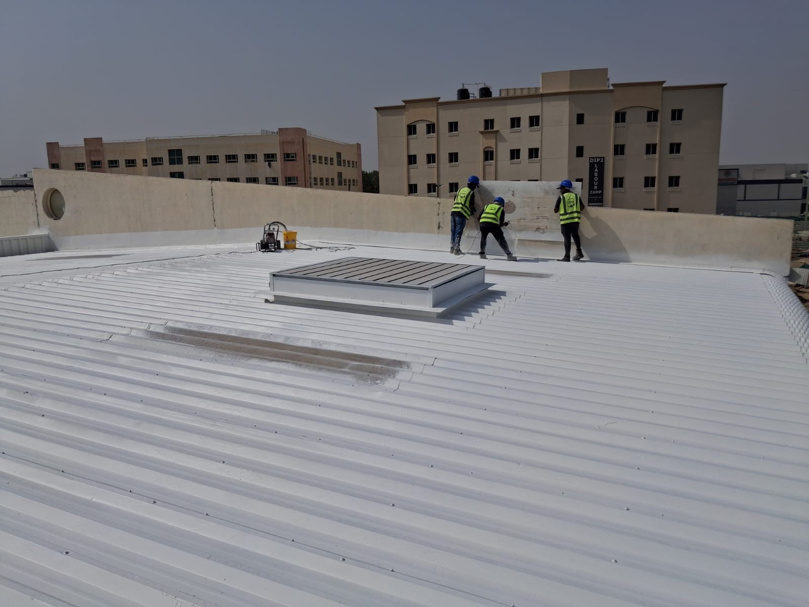 CoolRoof UAE crew finishing a 600 m2 warehouse roof with white reflective coating in Dubai Investment Park 2