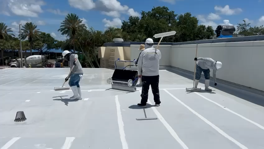 Workers applying reflective coating to a roof