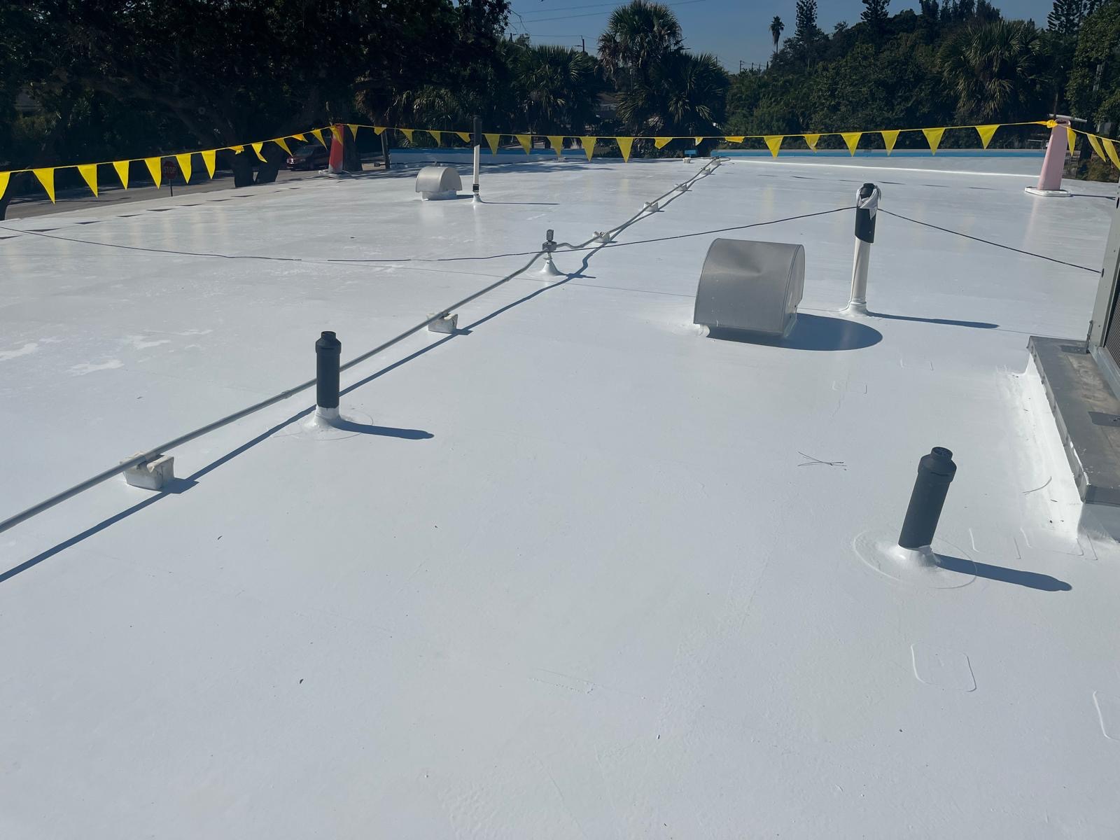 Clean white reflective coating applied around roof penetrations and details