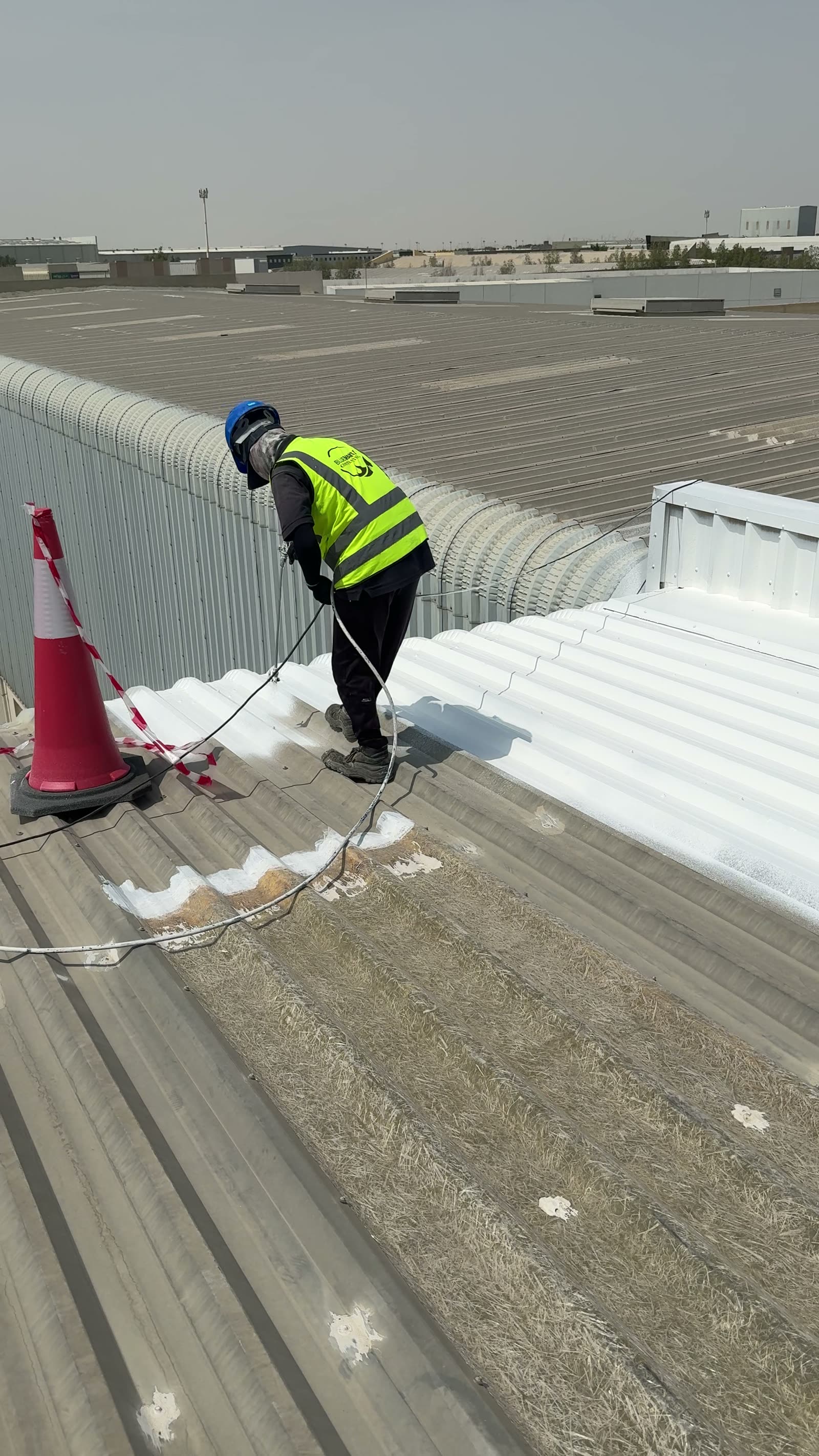 Boundary between untreated grey metal roof and the newly coated white surface